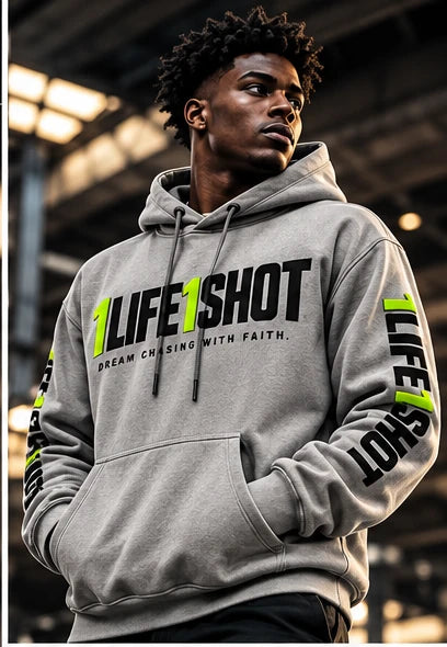 1Life1Shot athlete in a gray hoodie with the volt-accented 1LIFE1SHOT chest logo, striding forward through an industrial hall